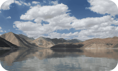 Scenic mountain landscape with a calm lake and cloudy sky.