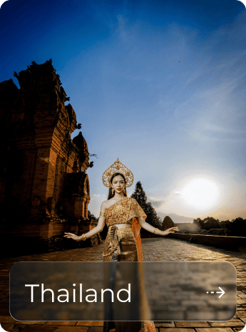 Traditional Thai dancer in ornate costume at historic site during sunset.